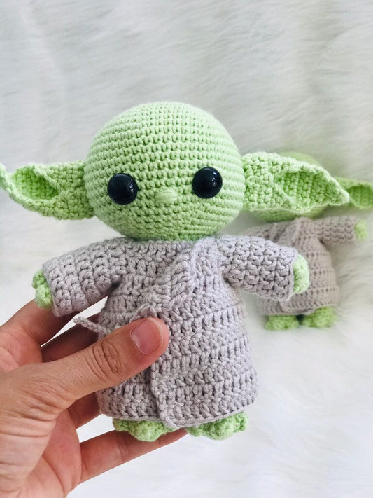 Handmade crochet green alien wearing a cozy jacket with intricate stitching.