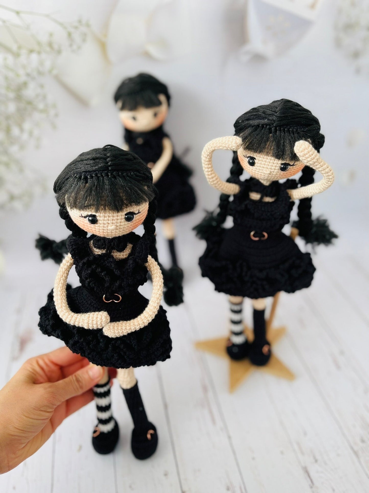 A handmade Amigurumi doll resembling Wednesday Addams with braided pigtails and a scowl