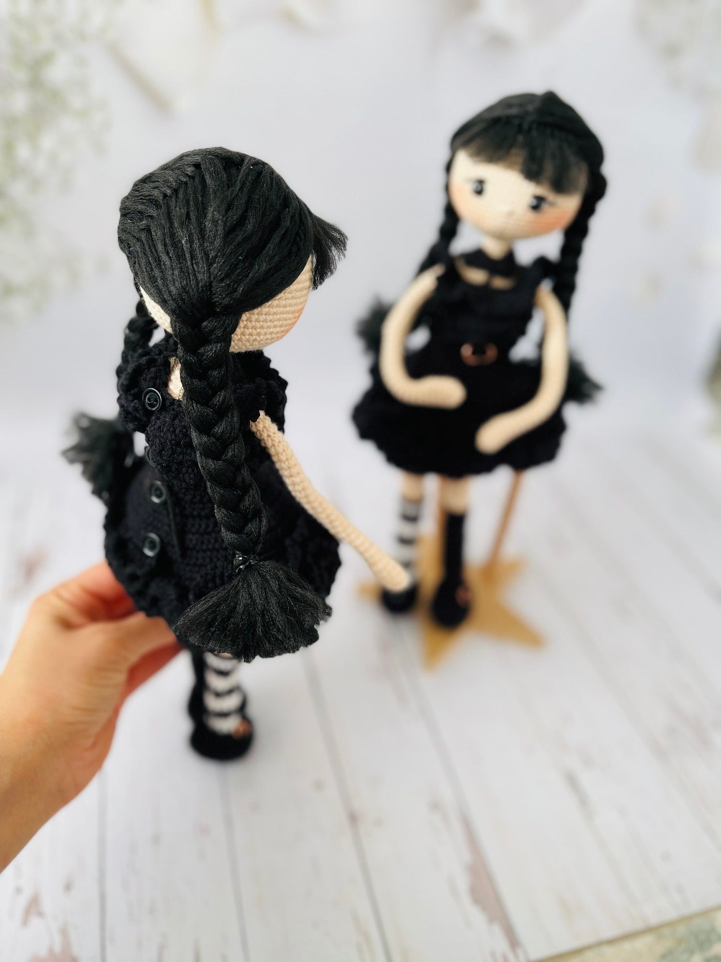 Wednesday Addams inspired doll with braided pigtails and a serious expression, made from crochet