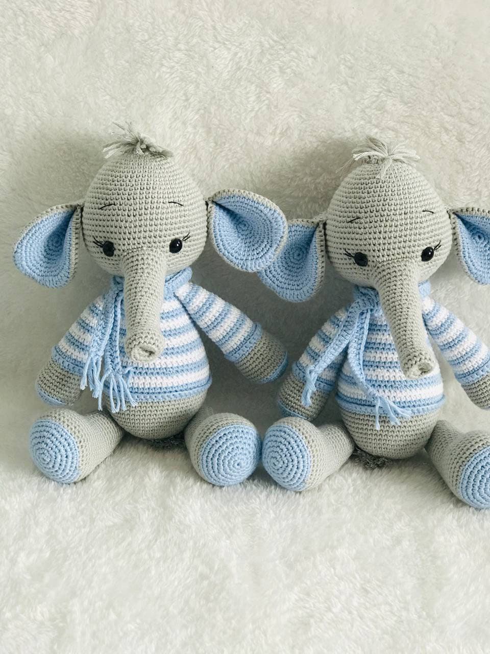 Close-up of a handmade crochet elephant toy featuring grey and yellow stripes and a white scarf