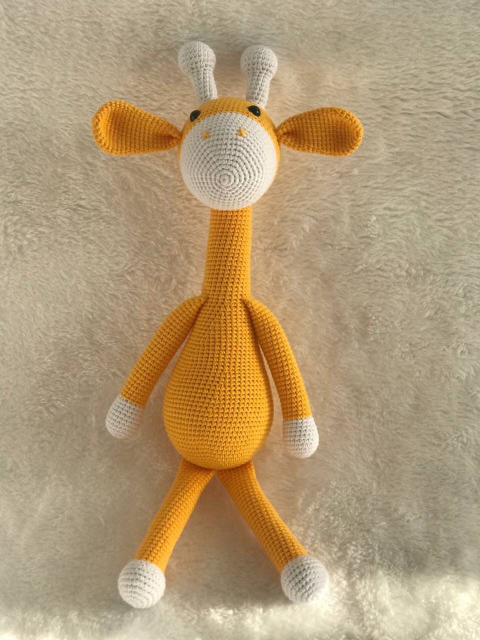 This is an instantly eye-catching a crocheted gold yellow giraffe with a white horn! The giraffe appears to have been made from soft, colorful yarn that's been cleverly shaped and manipulated by skilled hands into its gentle curves.