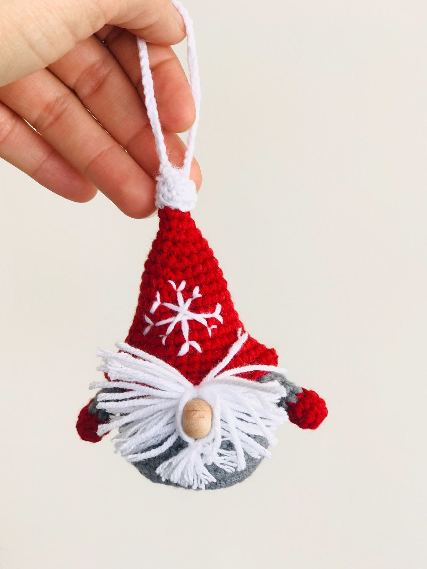 Handmade crochet Christmas decoration of a Scandinavian gnome, also known as a Gonk, with a red and white striped hat and a fluffy white beard. Perfect for adding a cozy and festive touch to your holiday decor. Made with love by a skilled artisan