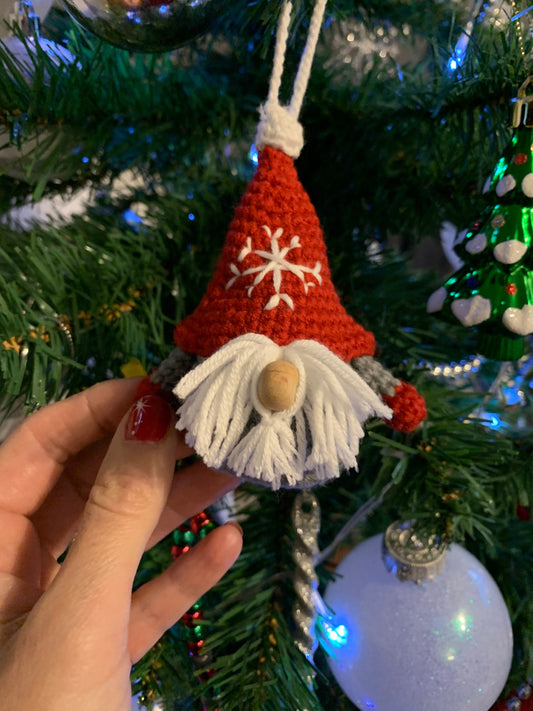 Handmade crochet Christmas decoration of a Scandinavian gnome, also known as a Gonk, with a red and white striped hat and a fluffy white beard. Perfect for adding a cozy and festive touch to your holiday decor. Made with love by a skilled artisan