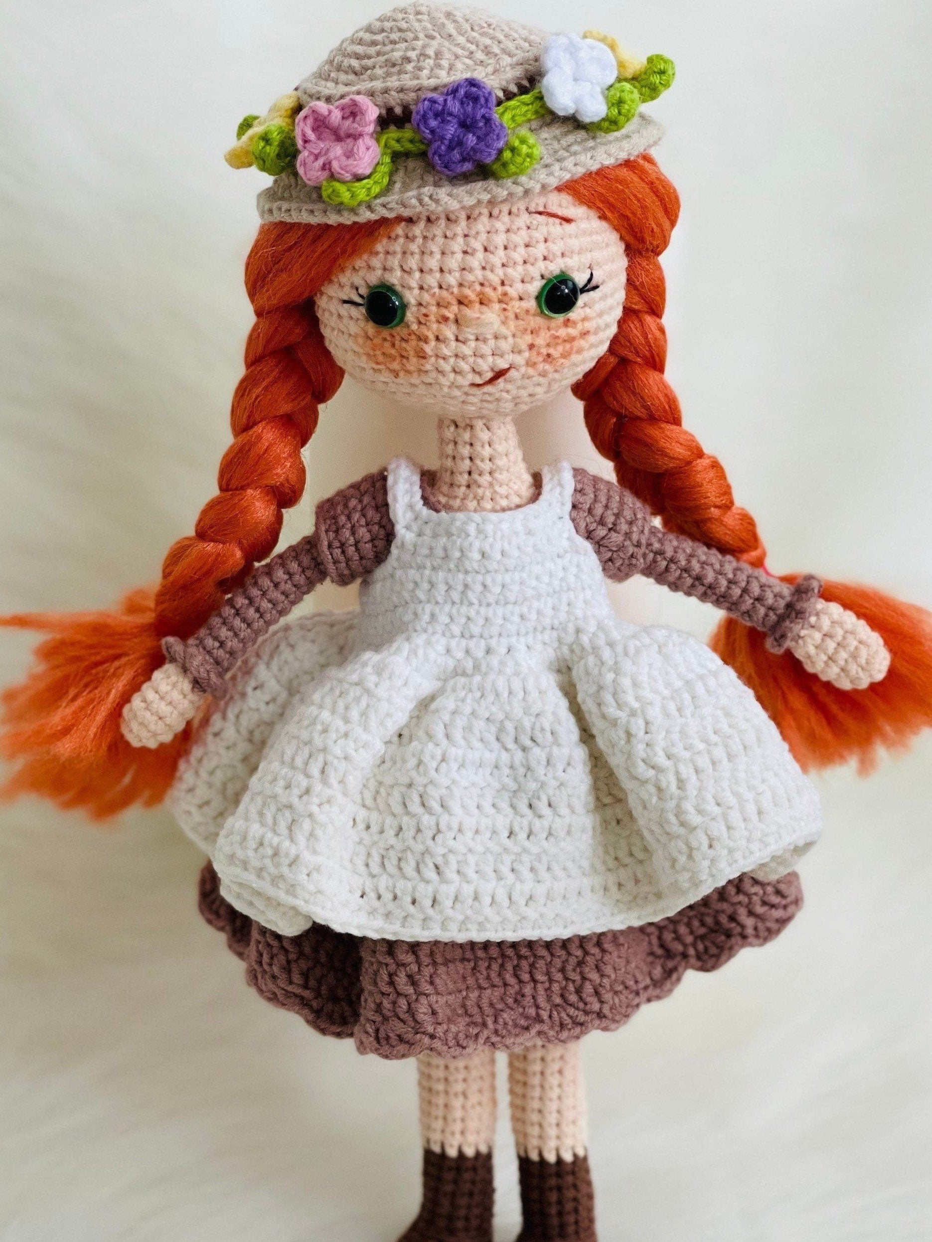 Crocheted Anne of Green Gables Doll with red hair, beige hat, and two dresses. Handmade with care to capture the essence of the beloved literary character. perfect for gifting to fans of the book series or anyone who loves dolls and handmade crafts.