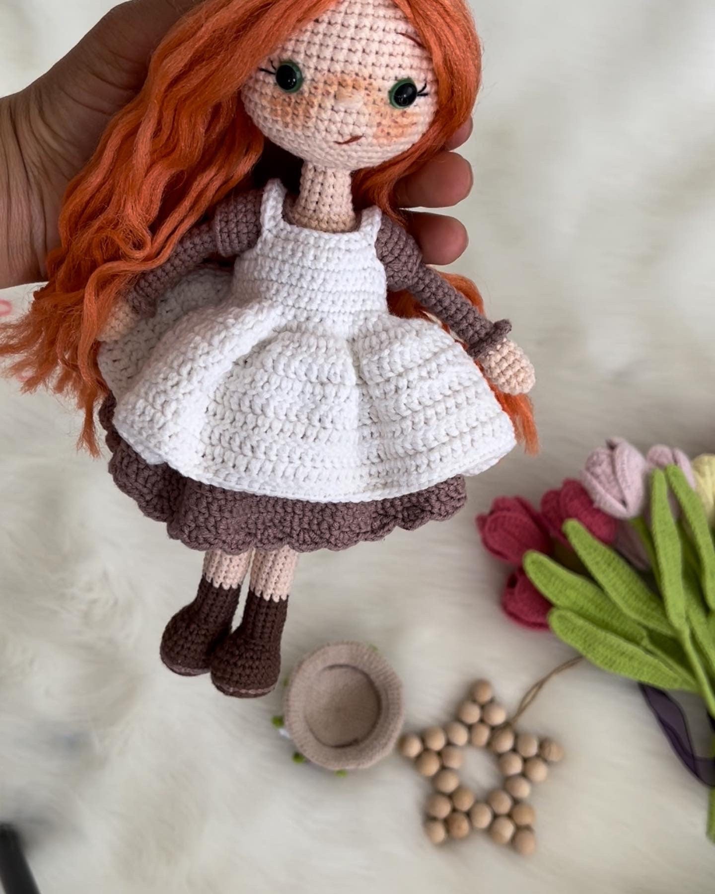 Crocheted Anne of Green Gables Doll with red hair, beige hat, and two dresses. Handmade with care to capture the essence of the beloved literary character. perfect for gifting to fans of the book series or anyone who loves dolls and handmade crafts.