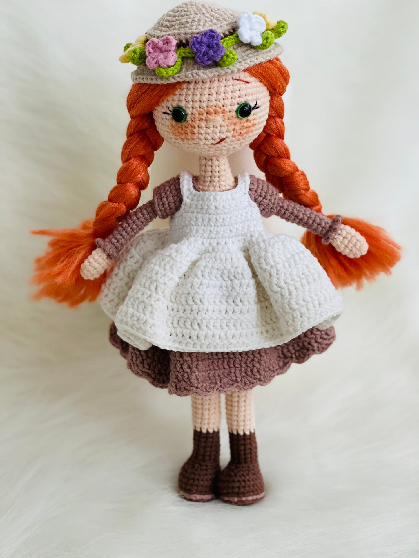 Crocheted Anne of Green Gables Doll with red hair, beige hat, and two dresses. Handmade with care to capture the essence of the beloved literary character. perfect for gifting to fans of the book series or anyone who loves dolls and handmade crafts.