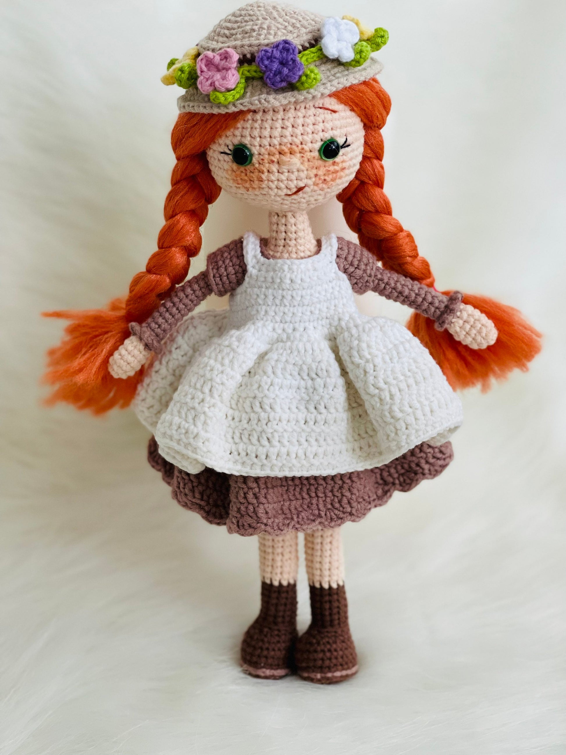 Crocheted Anne of Green Gables Doll with red hair, beige hat, and two dresses. Handmade with care to capture the essence of the beloved literary character. perfect for gifting to fans of the book series or anyone who loves dolls and handmade crafts.