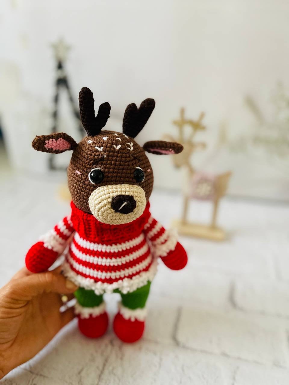 Handmade crochet reindeer toy in brown with a green and red sweater and black antlers. Standing at 25cm tall,amigurumi reindeer is the perfect addition to your holiday decor. Crocheted reindeer plushie with intricate stitching, eco-friendly materials
