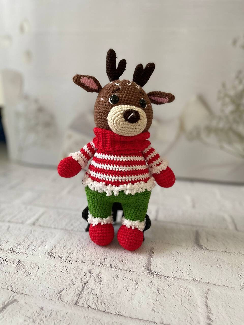 Handmade crochet reindeer toy in brown with a green and red sweater and black antlers. Standing at 25cm tall,amigurumi reindeer is the perfect addition to your holiday decor. Crocheted reindeer plushie with intricate stitching, eco-friendly materials
