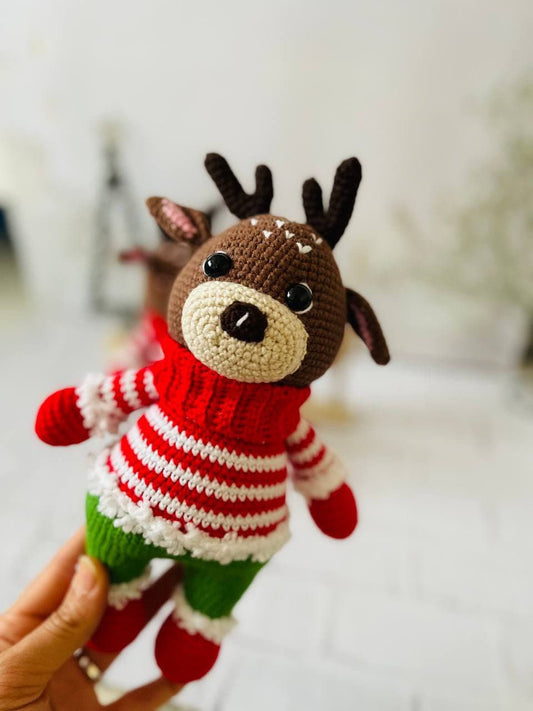 Handmade crochet reindeer toy in brown with a green and red sweater and black antlers. Standing at 25cm tall,amigurumi reindeer is the perfect addition to your holiday decor. Crocheted reindeer plushie with intricate stitching, eco-friendly materials