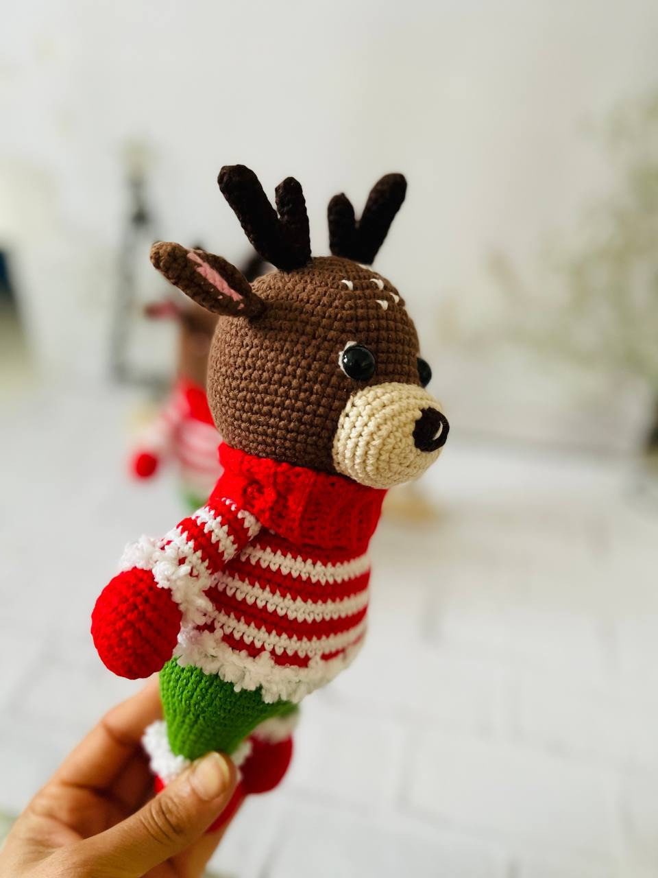 Handmade crochet reindeer toy in brown with a green and red sweater and black antlers. Standing at 25cm tall,amigurumi reindeer is the perfect addition to your holiday decor. Crocheted reindeer plushie with intricate stitching, eco-friendly materials