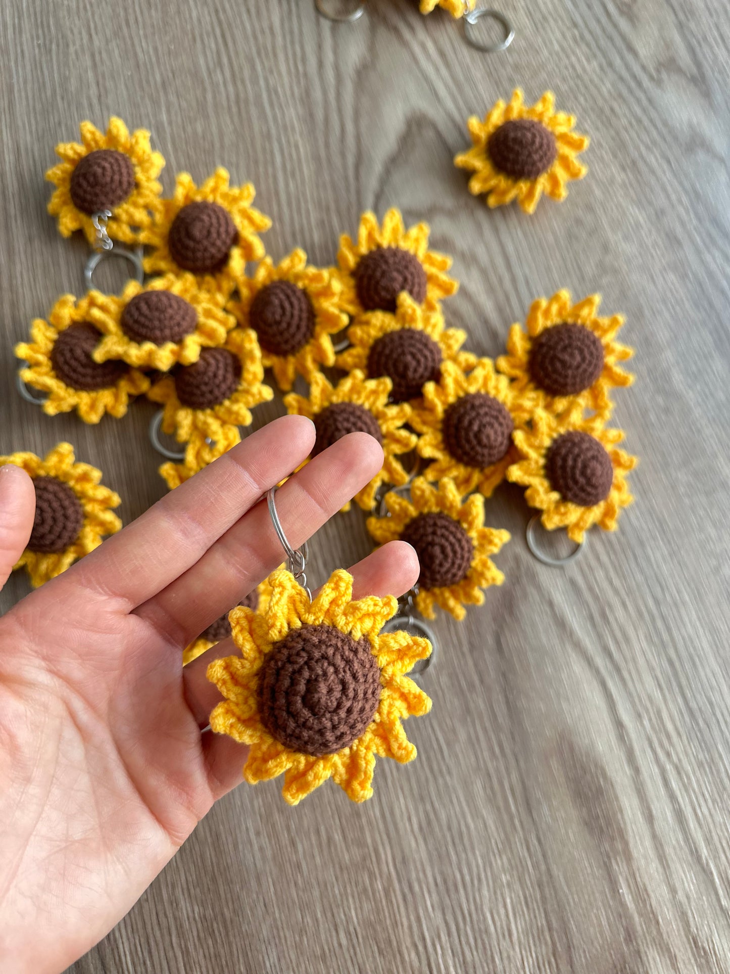 A handmade yellow crochet sunflower keyring with a tightly crocheted brown center.