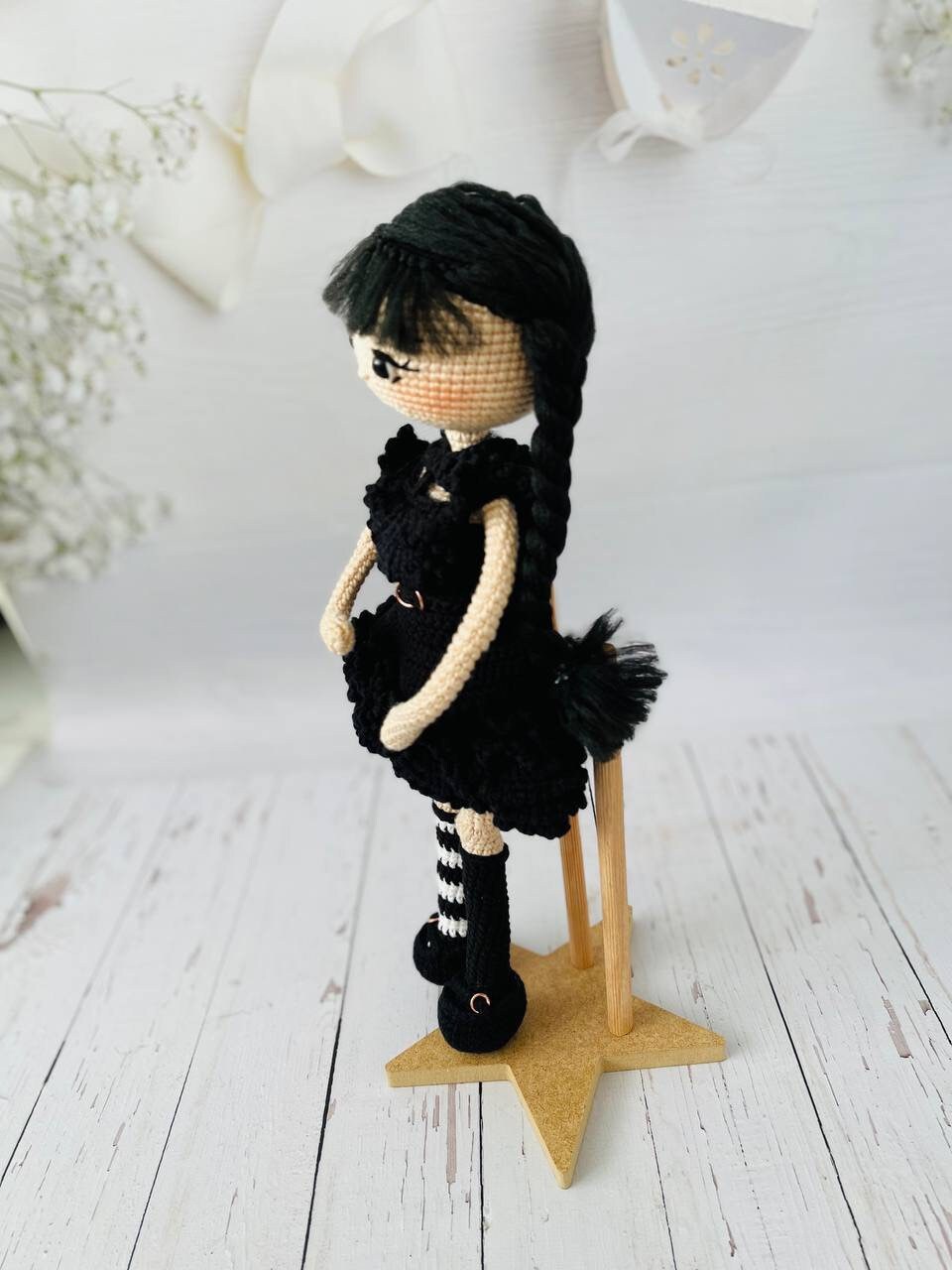 Close-up of a hand-crocheted Wednesday doll showing the intricate details of her dress and hair.