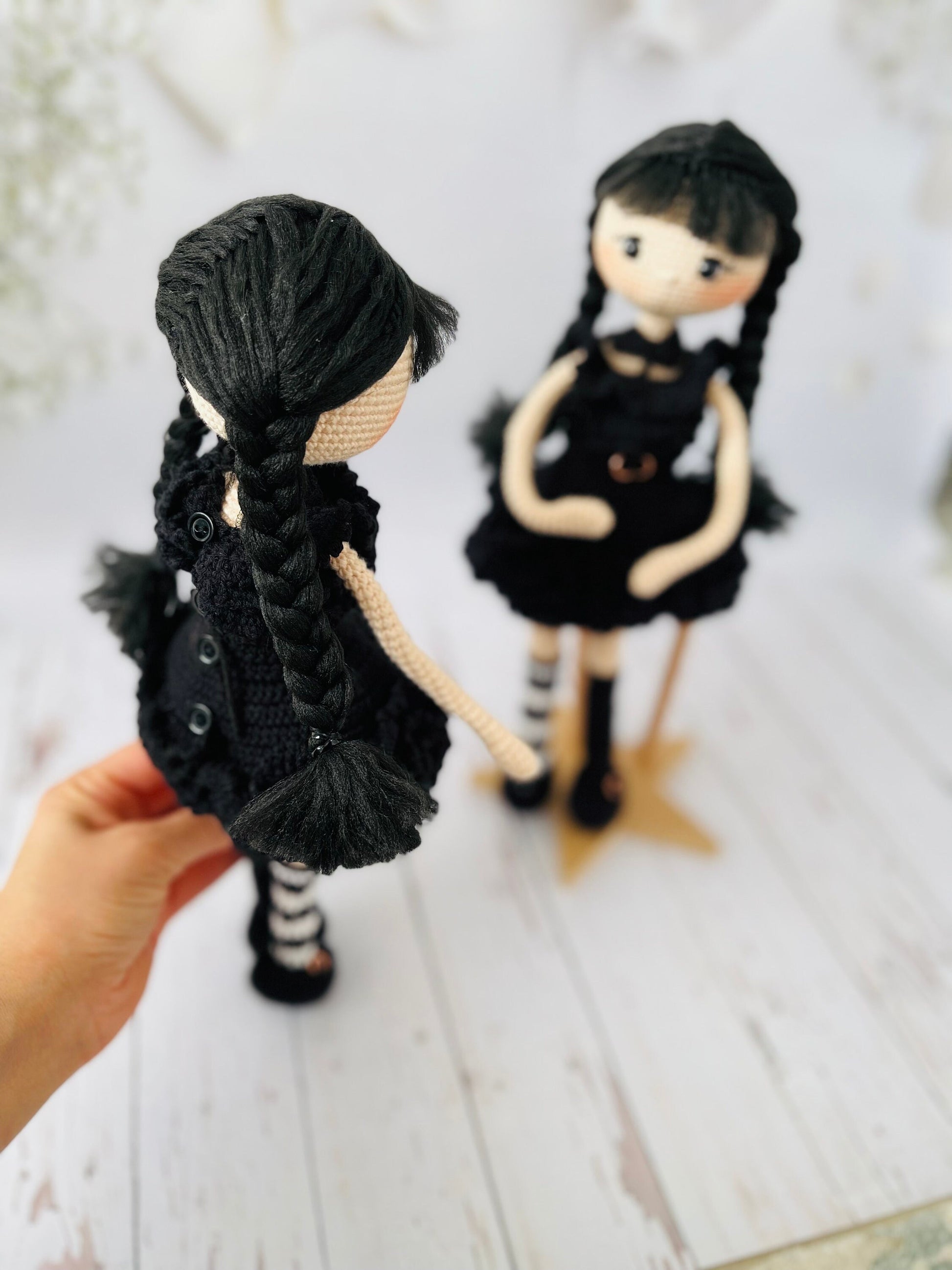 Wednesday Addams inspired doll with braided pigtails and a serious expression, made from crochet
